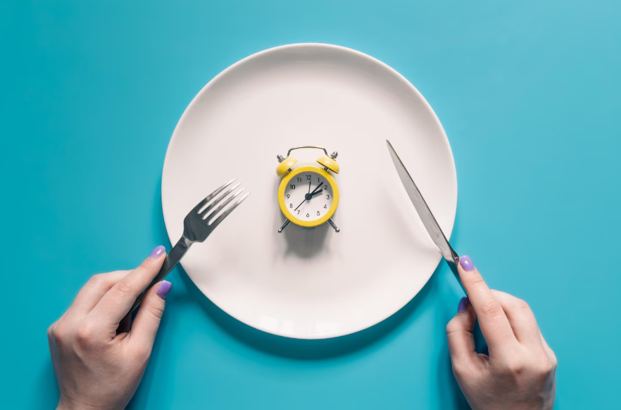 Clock on plate illustrating the science behind intermittent fasting and time-restricted eating patterns.