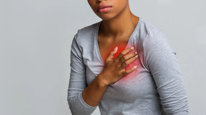 person holding chest showing heartburn symptoms and what causes acid reflux
